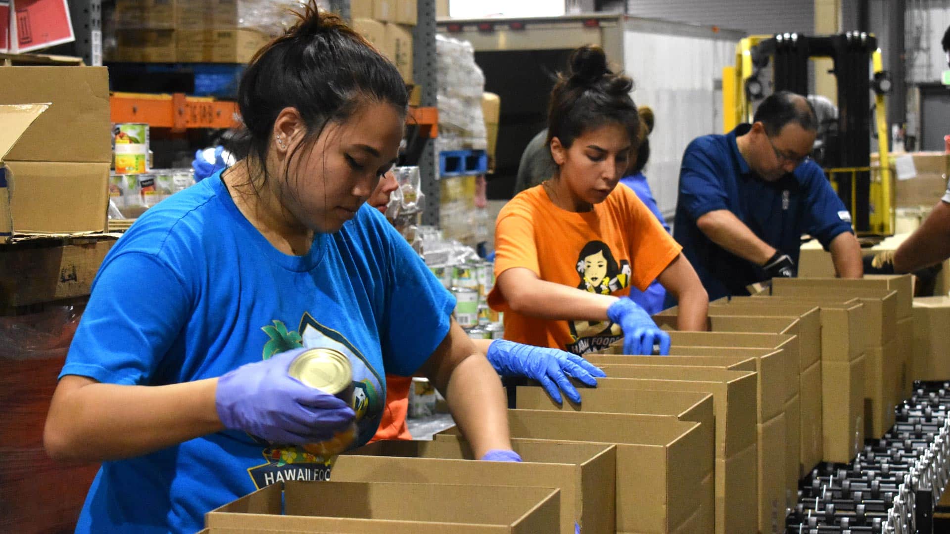 Hawaii Foodbank staff meticulously inspecting and preparing food items for distribution in Oahu's food bank warehouse.