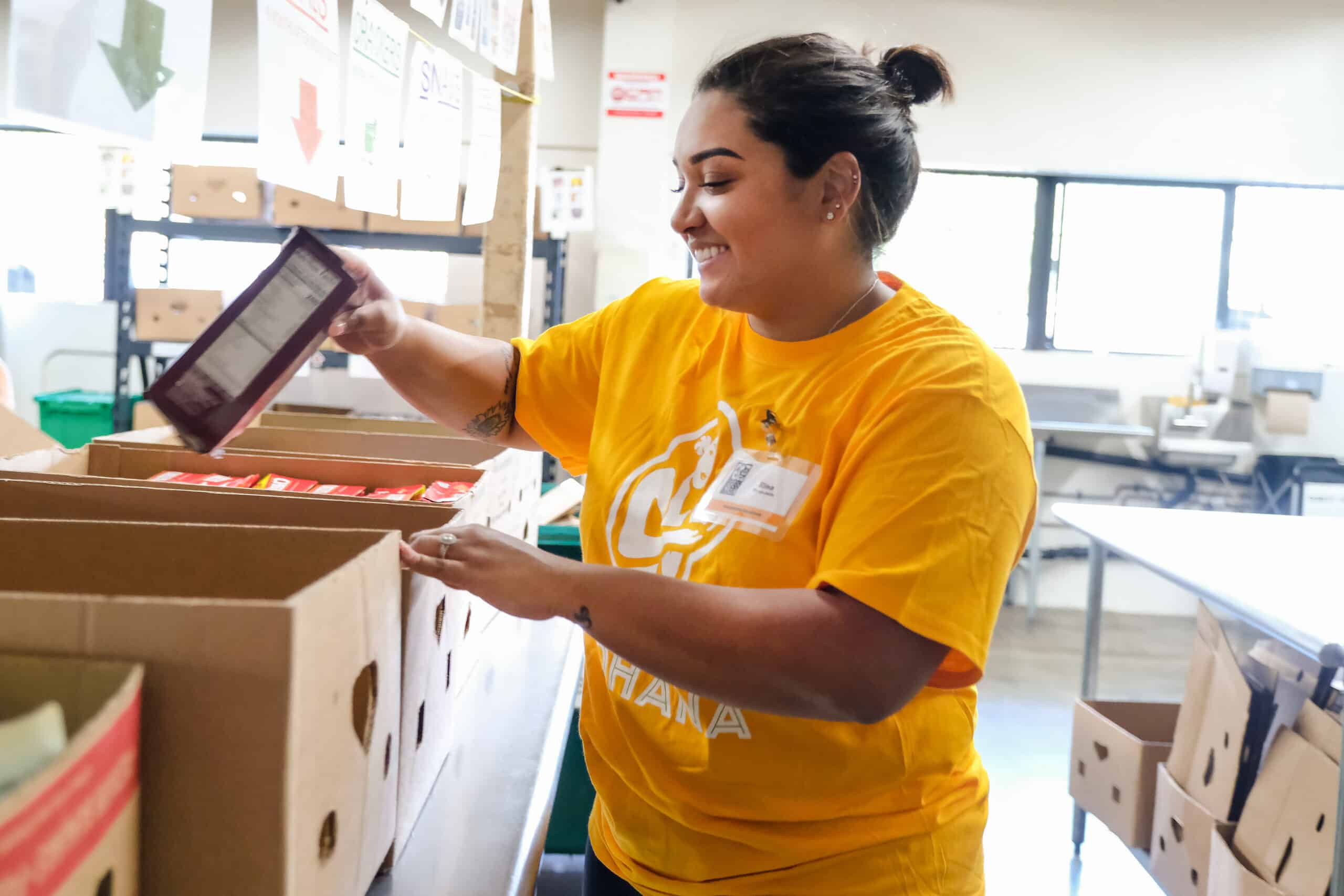 Volunteer Rina sorts boxed foods by cateogry.