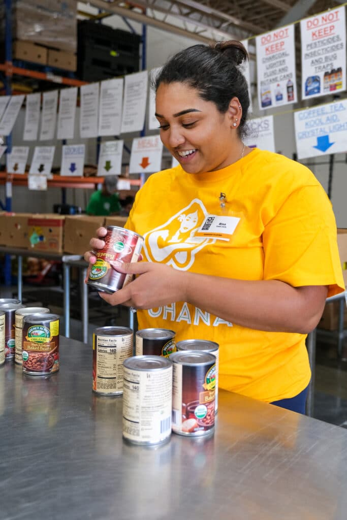 Foodbank volunteer Rina inspects a donated can of food.