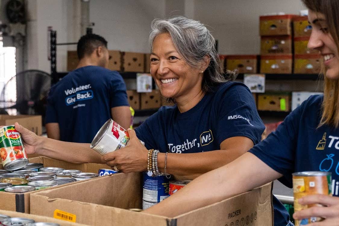 Smiling volunteers sort donations at the Hawaii Foodbank warehouse.
